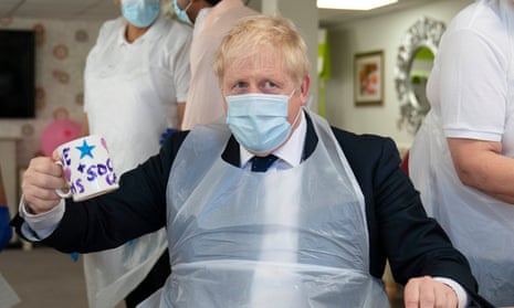 Boris Johnson in a mask and apron holding a painted mug in a care home