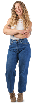 Ellie, wearing a white sleeveless top and jeans, with curly blond hair and her arms crossed