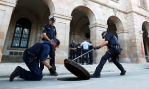 Officers from Catalonia’s regional police force, Mossos D’esquadra, search under a manhole cover outside the regional assembly in Barcelona on Tuesday.