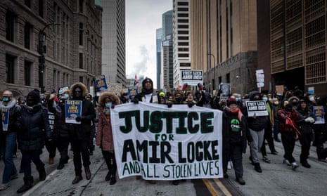 Demonstrators march behind  a banner reading 'Justice for Amir Locke and All Stolen Lives' during a rally in protest of the killing of Amir Locke by police, outside the Hennepin county government center in Minneapolis on Saturday.