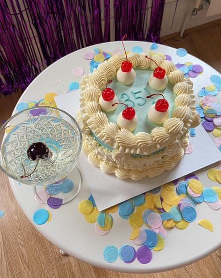 An elaborately piped off-white icing-covered round cake with decorative cherries on top and a pale blue top with the figure 35! written on