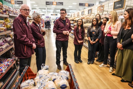 Andy Burnham, Sainsbury's staff and half a dozen young people stood in the bread aisle in a supermarket.