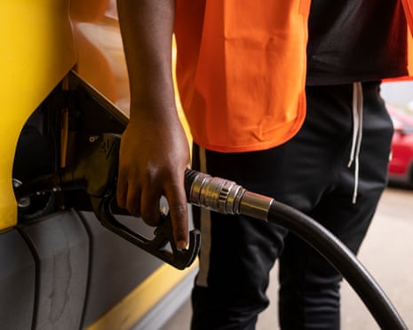 A man puts fuel in his van on a petrol station forecourt.