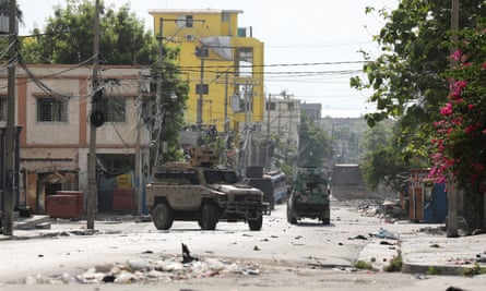Military vehicles on a rubble-strewn street