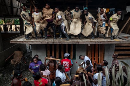 Inhabitants of the Juntas village gather in two rows, one standing on a wooden panel above the others.