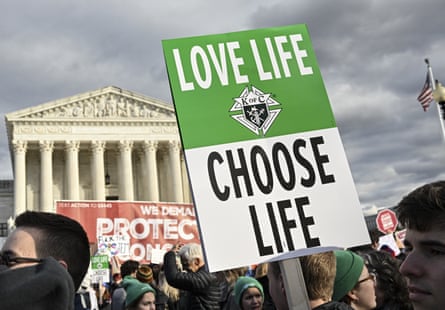 person holds sign that says ‘love life choose life’ in front of supreme court