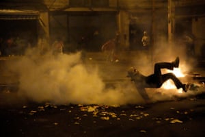 A demonstrator falls to the ground amid smoke