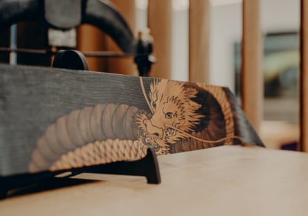 A wood panel engraved with a detailed dragon design, in a Rolls-Royce workshop