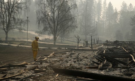 A firefighter searches for human remains in a trailer park destroyed in the Camp fire.