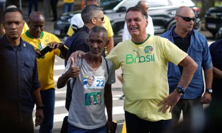 Jair Bolsonaro smiles as he poses with a supporter making a thumbs up gesture