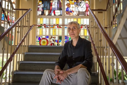 Axel Drieschner sitting on steps in the museum with a stained glass window behind him