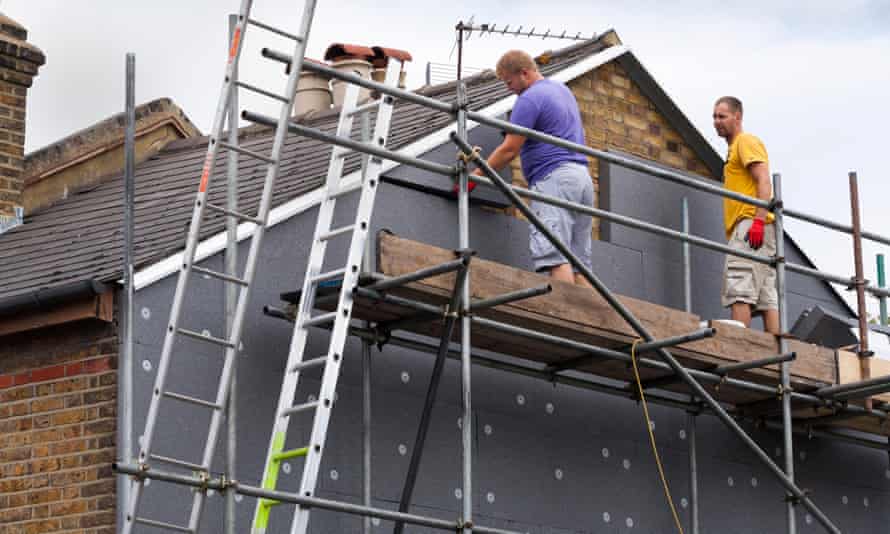 Builders attach insulation boards to the gable end of a Victorian terraced house.