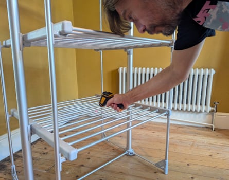 A person tests the temperature of a heated clothes airer with an infrared thermometer