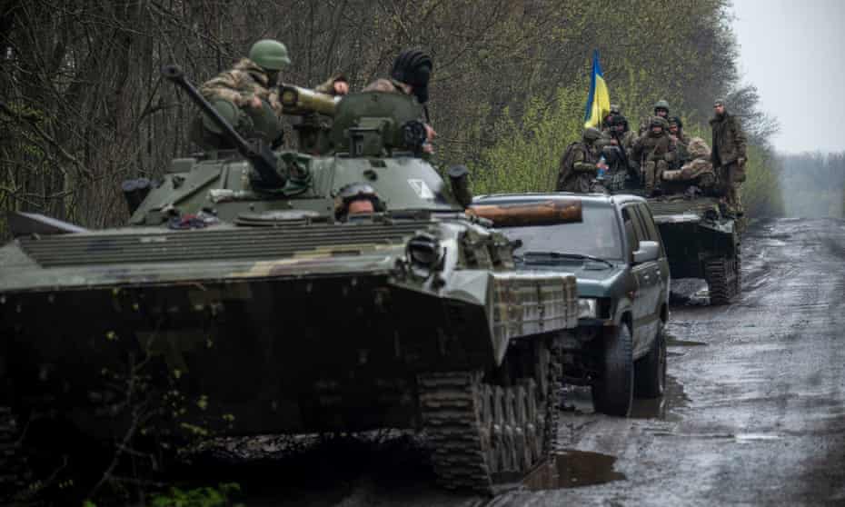 Ukrainian servicemen sit atop an armoured fighting vehicle, as Russia’s attack on Ukraine continues