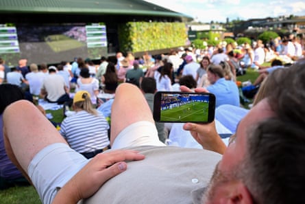 A fan on Henman Hill watches the football on his phone