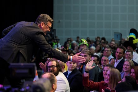 Andy Burnham reaches out to Jo Platt in a crowd from his position on a stage
