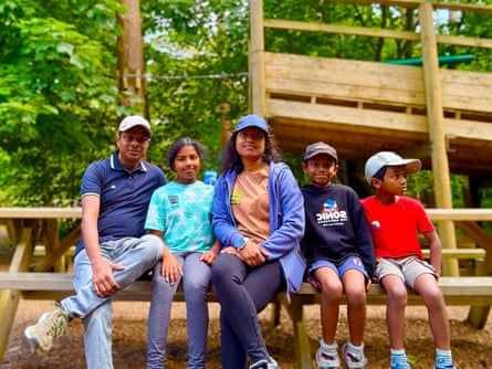 Samarasinghe with his wife and three children, sitting in a row on a wooden bench outdoors
