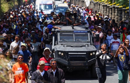 Protesters march alongside a Madagascar military vehicle