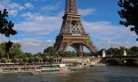 The Eiffel Tower, with the Olympics logo on it, on the banks of the Seine