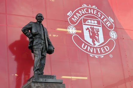 The Sir Matt Busby statue alongside the Manchester United club crest at Old Trafford