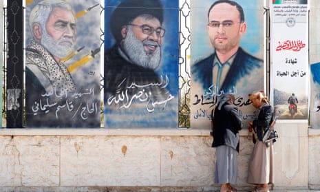Armed Houthi supporters stand near paintings depicting (L-R) the slain Iranian Gen Qassem Suleimani, Hezbollah’s Hassan Nasrallah and the Houthis’ political council head Mahdi al-Mashat on a street in Sana’a, Yemen.