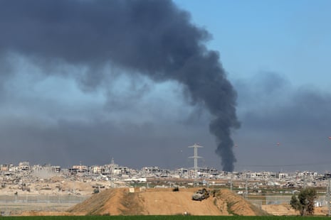 Smoke rises in the background with damaged buildings in the Shujaiya neighbourhood in the foreground