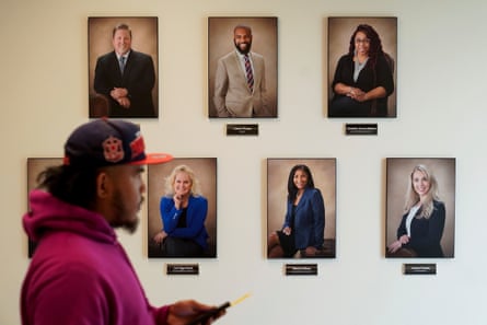 A man wearing a hat walks by a wall of portraits.