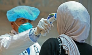 Kuwaiti health ministry workers scan employees and visitors of the ministries complex, as they arrive to their work, in Kuwait City on March 4, 2020.