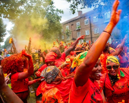 Notting Hill carnival attenders covered in orange paint and letting of smoke grenades