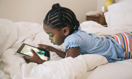 Girl playing with tablet om bed