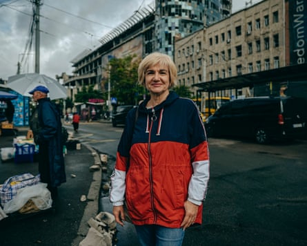 A blond woman in a blue, red and white hoodie standing at the outskirts of a market