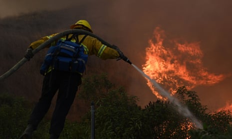 firefighter sprays the flames of a wildfire in California.