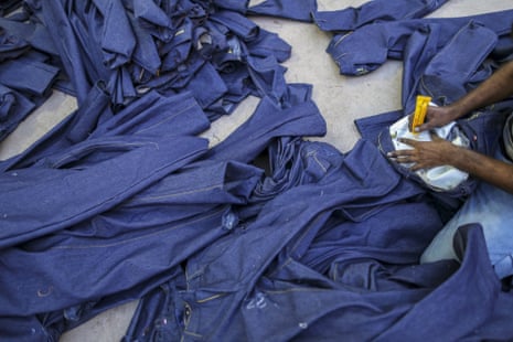 A worker writes a number on the inside of a pair of jeans at a factory in Ballari, Karnataka.