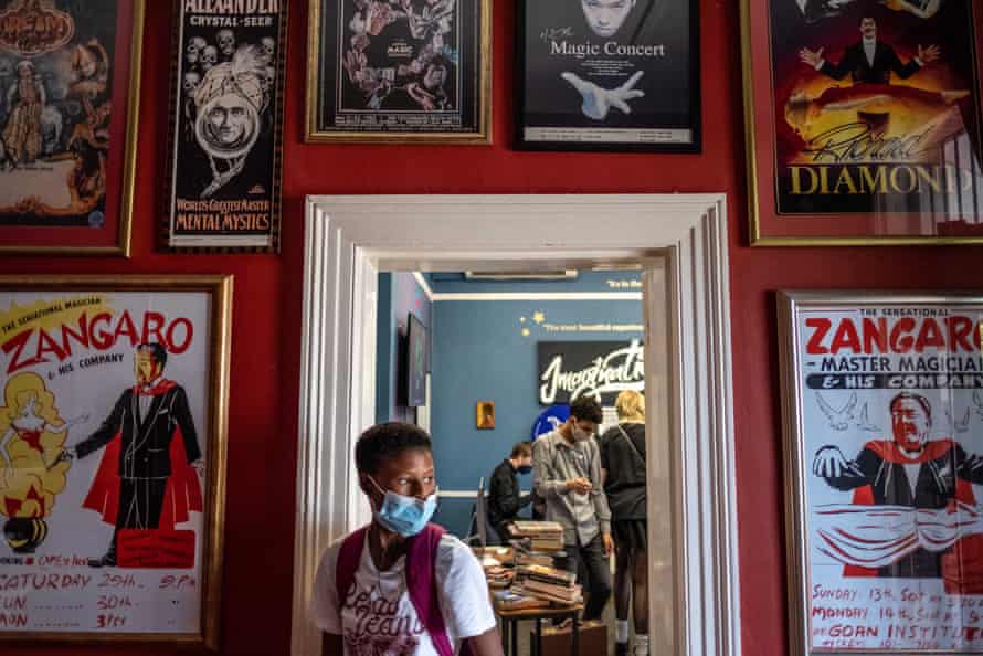 Students leave a classroom with walls covered with posters of illusionists.