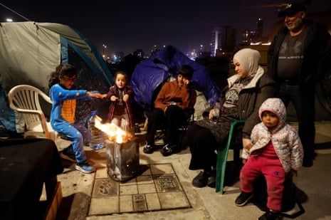 A displaced family with children warm themselves around a fire at a makeshift camp in the waterfront area of Beirut, Lebanon.