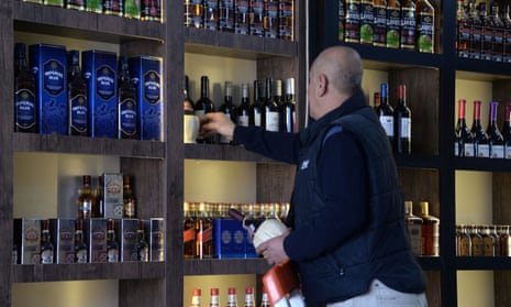 A shop worker arranges bottles on a shelf at a liquor shop in Mosul.