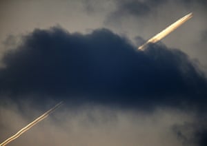 An aircraft flies over Frankfurt, leaving contrails above the cloud