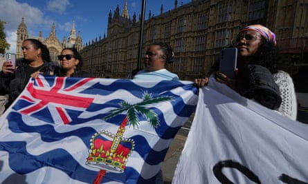 Chagossians protest outside the Houses of Parliament: four women hold the islands’ flag and a banner