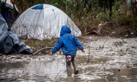 A refugee child walks in the mud in refugee camp near Dunkirk, northern France.