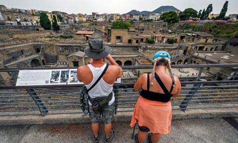 Two people stand on a balcony and overlook buildings in Ercolano