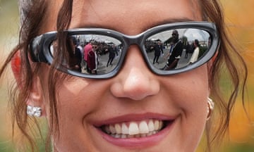 Closeup of the face of a smiling Adèle Exarchopoulos. Other people at the photo call can be seen in the mirrored lenses of her sunglasses, as well as a scrum of photographers