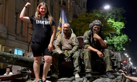 A girl poses with Wagner soldiers on a tank.