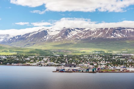 Town on edge of sea/inlet with snowy mountains behind