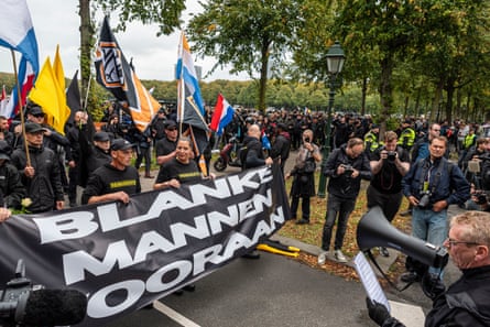 A group of protesters carrying a banner which says 'blanke mannen ooraan' in Dutch.