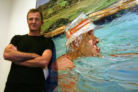 Nicholas Harding is standing of his painting of a man swimming in blue water wearing a bucket hat. Harding is wearing a black shirt and has his arms crossed