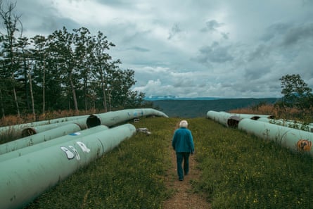 a man walks along a grassy area with pipes on either side of him