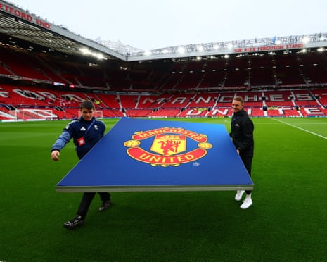 A Manchester United sign is carried on the Old Trafford pitch