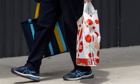 People carry plastic shopping bags outside of a Woolworths store