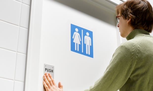 A man pushing a toilet door with both male and female icons on it