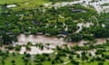 Brown floodwater in green land and semi-submerged dwellings